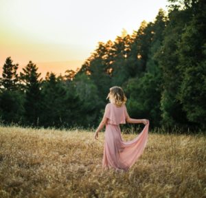 woman in pink dress standing on brown grass field during daytime