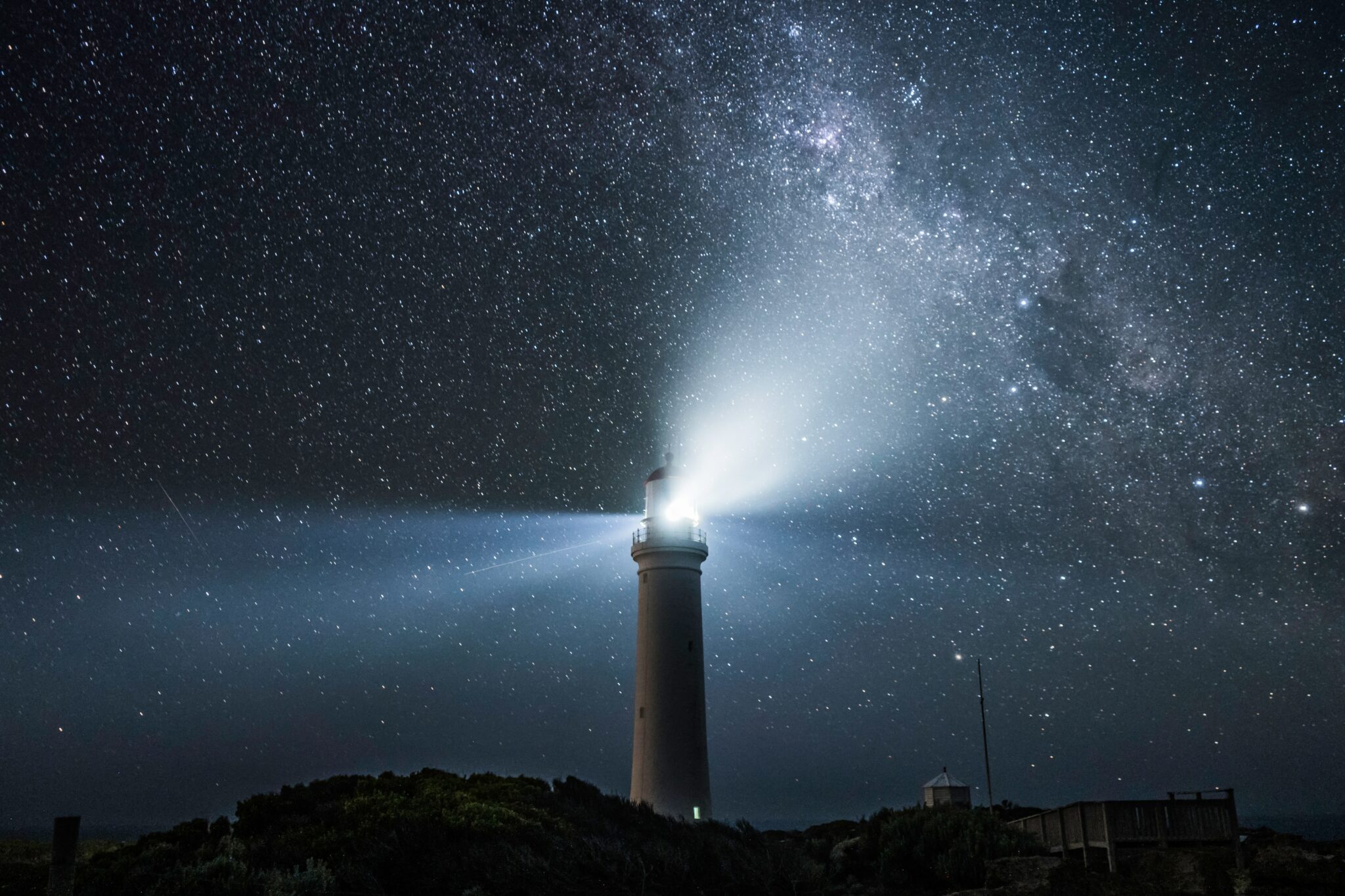 a lighthouse under a night sky filled with stars