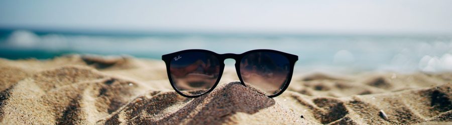 black Ray-Ban Wayfarer sunglasses on beach sand