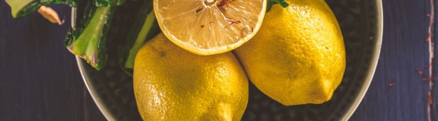 sliced lemon and green leaves on gray stainless steel bowl